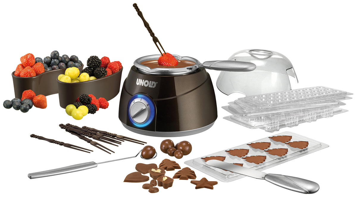 Die Unold Chocolatier Weihnachtsedition zeigt einen zentralen Schmelztiegel, verschiedene Schokoladenformen, schokolierte Früchte und Beeren, Utensilien und Pralinen in verschiedenen Formen auf weißem Hintergrund.