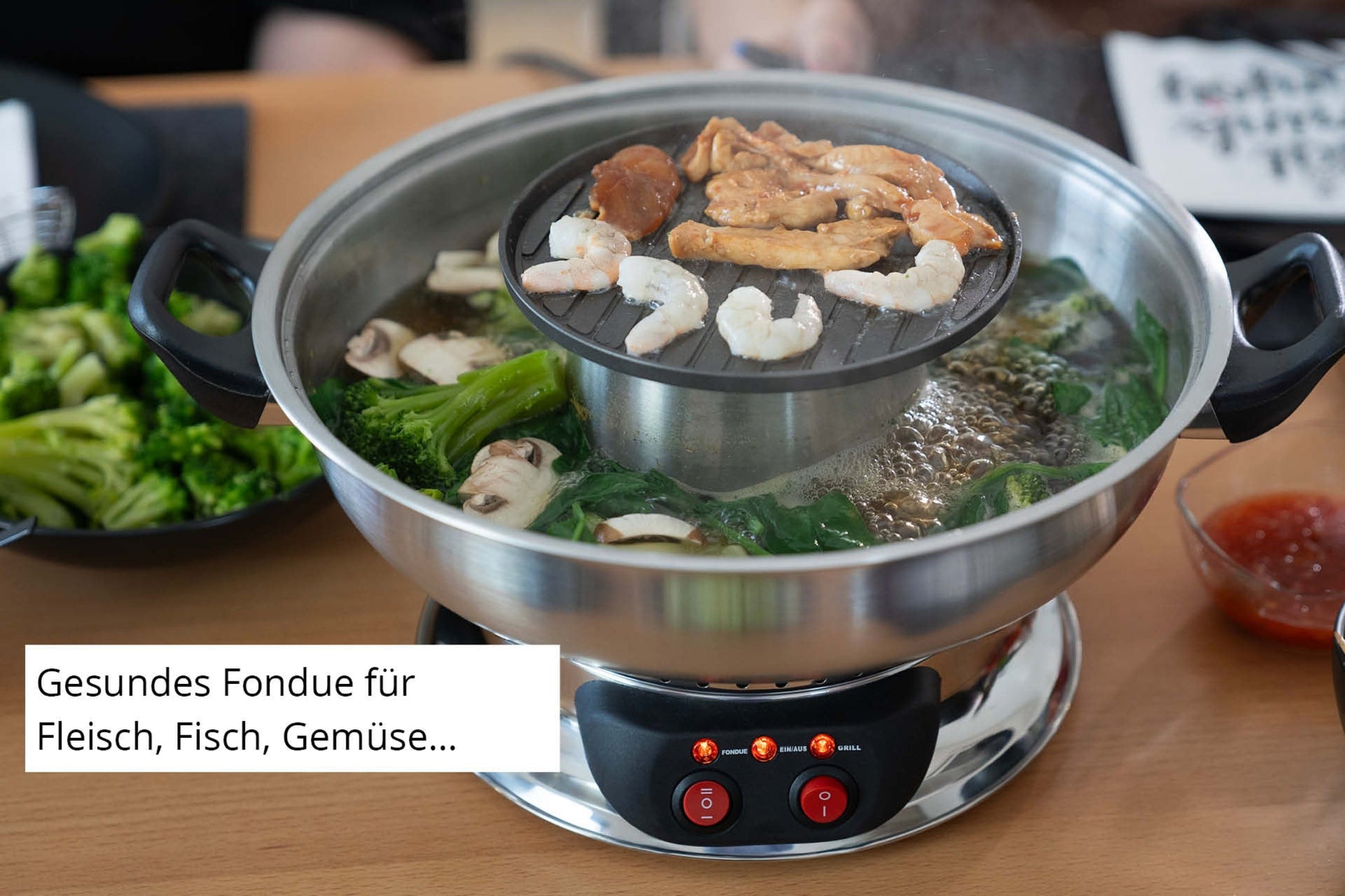 Das Unold Asia-Fondue verfügt über einen Grill für Garnelen, Fleisch und Gemüse. Frisches Gemüse, Pilze und Brokkoli sind abgebildet. Der deutsche Text lautet: Gesundes Fondue für Fleisch, Fisch, Gemüse.