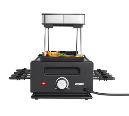 Vorderansicht des Unold Raclette Smokeless inklusive Raclette Buch, einem schwarzen Raclette-Grill mit silberner Oberseite, Grillspießen und Grillgut darüber, verlängerten Seitenablagen sowie einem Leistungsregler und einer Kontrollleuchte auf der Vorderseite.