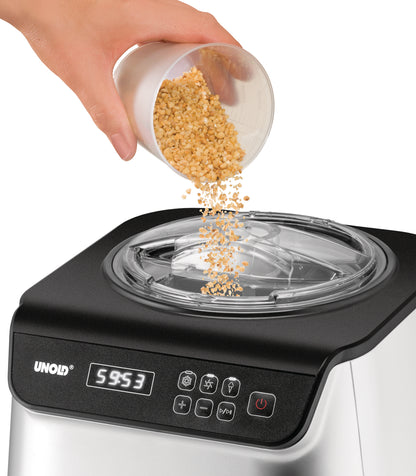 Eine Hand schüttet gehackte Nüsse aus einem kleinen Becher in die Eismaschine Unold Eismaschine Uno inklusive Eisbuch 1,2 L, die über eine digitale Anzeige und Bedientasten auf der Vorderseite verfügt.