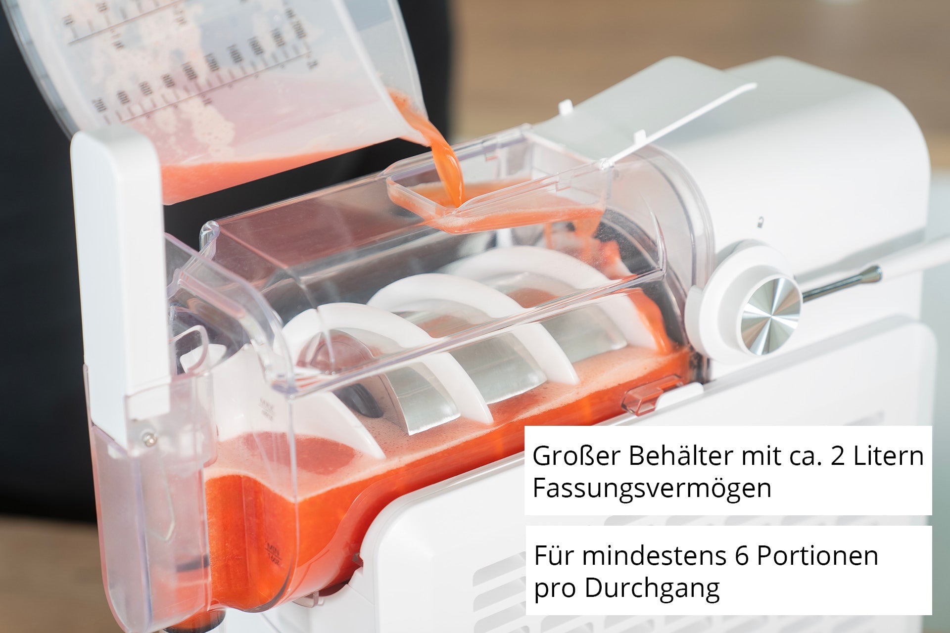 Eine Nahaufnahme der Unold Slush-Eismaschine Susi zeigt das Einfüllen einer Orangenmischung. Deutscher Text: Großer Behälter mit ca. 2 Liter Fassungsvermögen. Für mindestens 6 Portionen pro Durchgang.