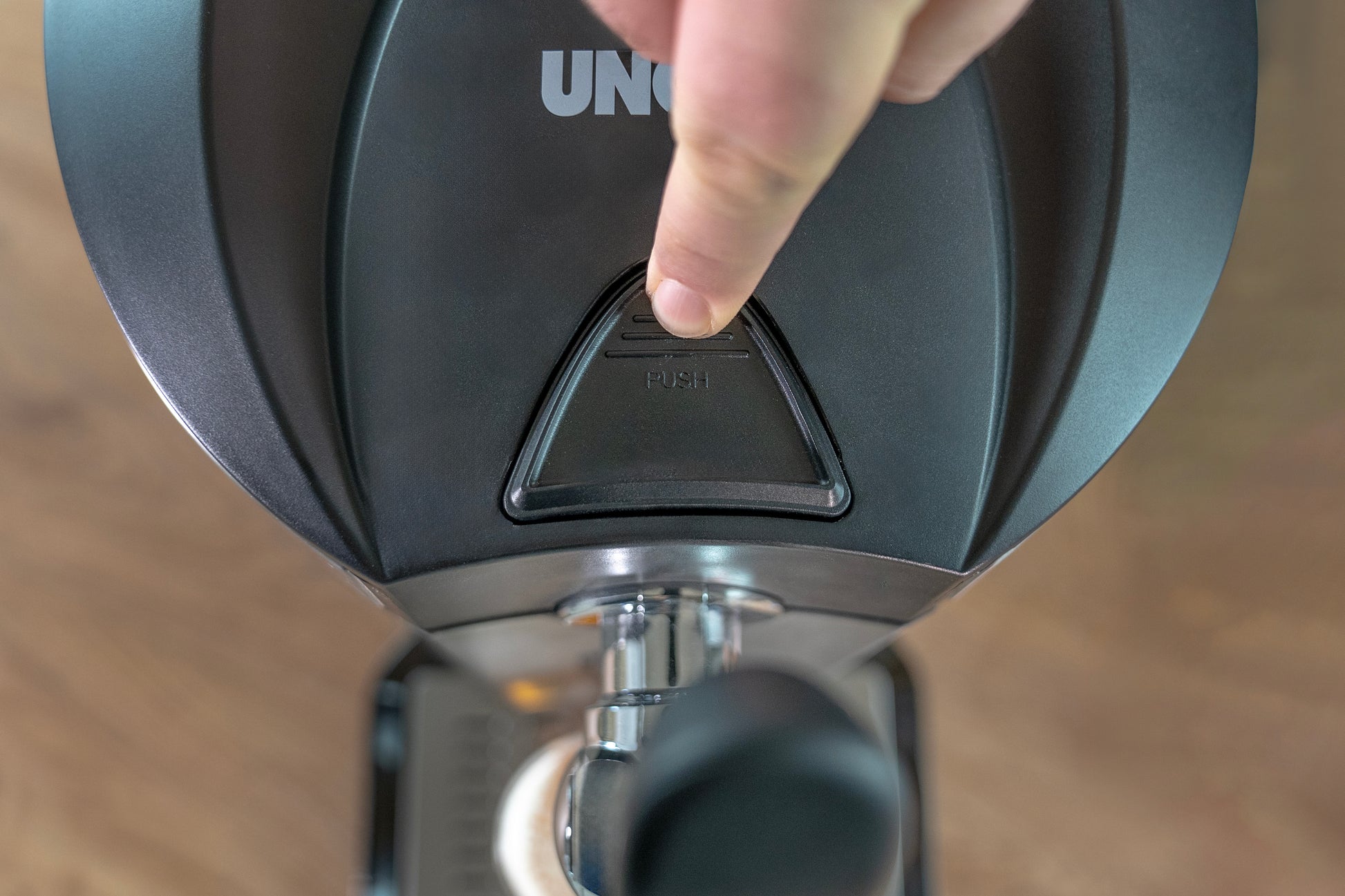 Eine Nahaufnahme des Fingers einer Person, die den PUSH-Knopf an der Unold Bierzapfanlage Franzl drückt, von oben gesehen.