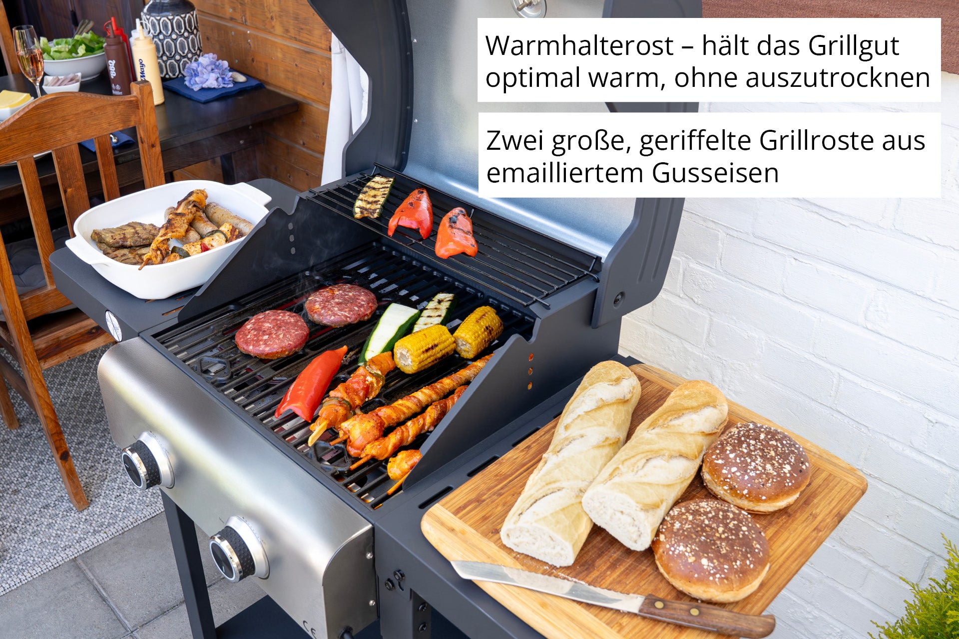 Der Unold Barbecue Grill-Wagen Buddy grillt Burger, Würstchen, Gemüse und Spieße, mit Brot und Brötchen auf dem Beistelltisch. Der deutsche Text hebt die Funktionen des Grills hervor.