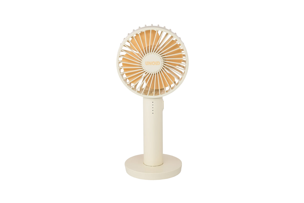 Der Unold Handventilator Breezy II ist ein beigefarbener, handgehaltener elektrischer Ventilator mit einer runden Basis, einem zylindrischen Griff und einem kreisförmigen Kopf mit eng beieinander liegenden Flügeln. In der Mitte des Ventilators ist "UNOLD" aufgedruckt. Der Hintergrund ist weiß.