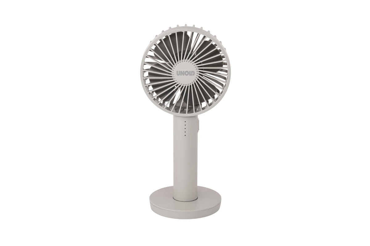 Der Unold Handventilator Breezy II ist ein kompakter, weißer, tragbarer elektrischer Ventilator mit einem kreisförmigen Gitter und einem aufrechten, runden Sockel, der auf einem schlichten weißen Hintergrund abgebildet ist.