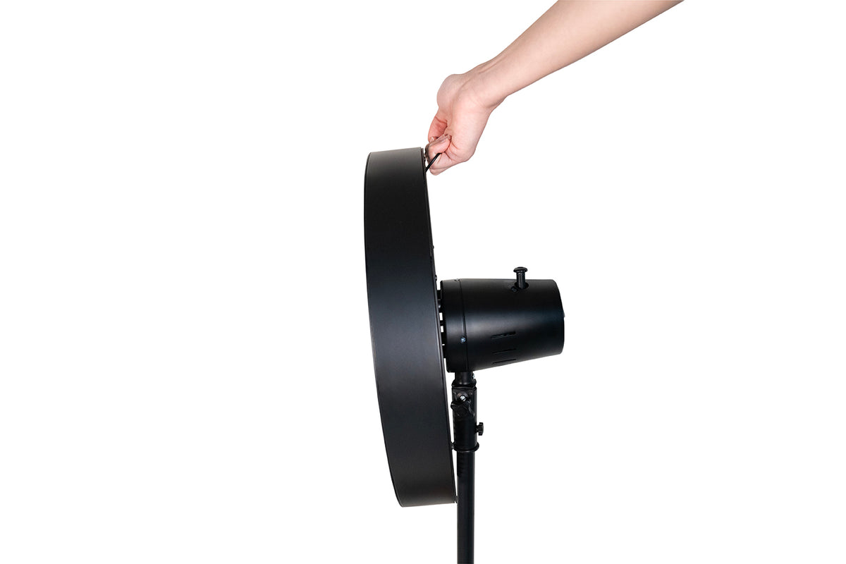 Eine Hand richtet die Oberseite des Unold Standventilators Black Steel aus, einem runden schwarzen Ventilator, der auf einem Ständer montiert ist und sich von einem schlichten weißen Hintergrund abhebt.