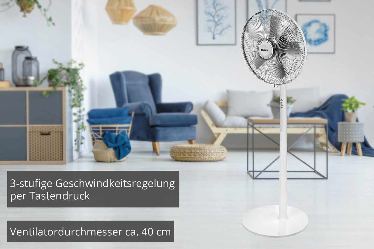 Der weiße STANDVENTILATOR Silverline von Unold steht im modernen Wohnzimmer mit blauen Sesseln, kleinem Tisch und Wandkunst. Deutsche Texte heben die 3 Geschwindigkeitsstufen und den 40 cm Durchmesser hervor.