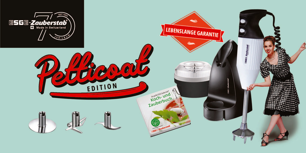 Werbebild für den Stabmixer ESGE Zauberstab Petticoat Edition mit Gerät, Zubehör, Kochbuch, Etikett mit lebenslanger Garantie und einer Frau in einem Vintage-Kleid mit Punkten, die verspielt posiert.