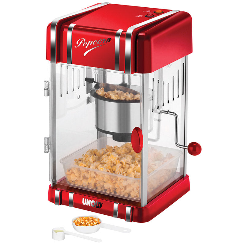 Der Unold Popcornmaker Retro ist eine rot-silberne Popcornmaschine mit transparenter Tür, einer Popcornkammer aus Metall und einem mit Popcorn gefüllten Tablett. Vorne befinden sich ein Messlöffel und ein kleiner Becher mit Popcornmais.