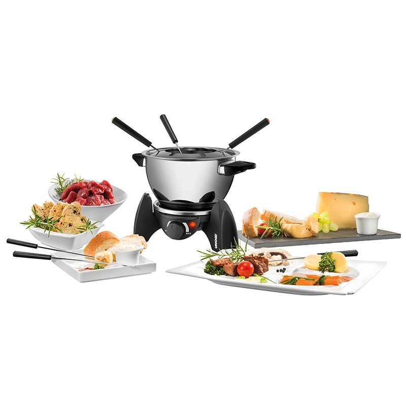 Das Unold Fondue-Set wird mit vier Gabeln geliefert und wird auf einem weißen Hintergrund präsentiert, umgeben von ordentlich angeordneten Tellern mit rohem Fleisch, Brot, Käse, Soßen, Gemüse und Trauben.