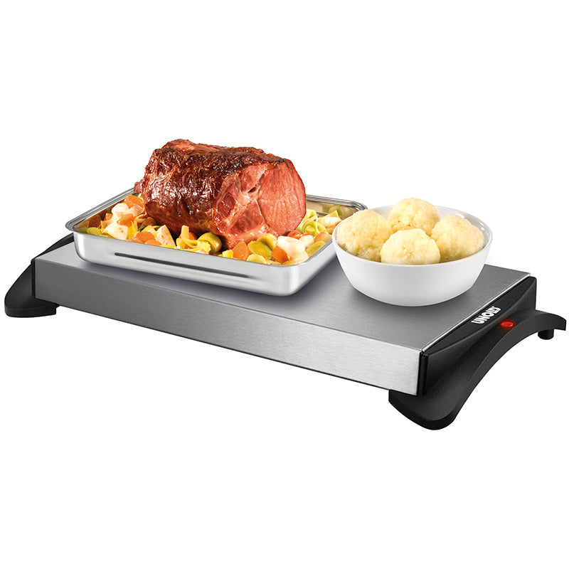 Die Unold Warmhalteplatte verfügt über ein Edelstahltablett mit schwarzen Griffen und einer roten Kontrollleuchte. Hier zu sehen ist sie beim Warmhalten von gebratenem Fleisch, Gemüse und runden Knödeln in einer weißen Schüssel.