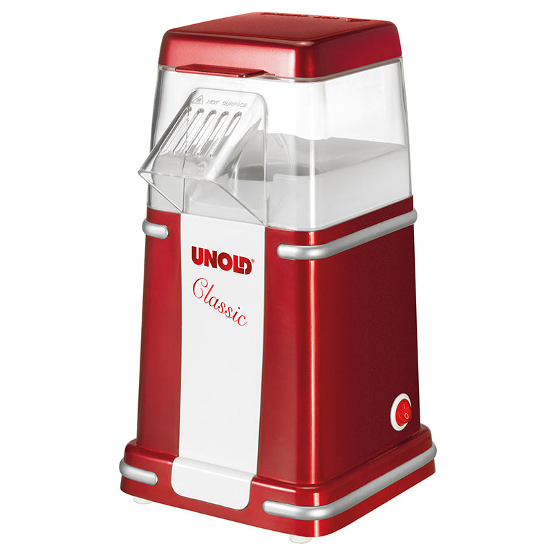 Der Unold Popcornmaker Classic ist rot und weiß und verfügt über eine transparente Oberseite, einen schrägen Deckel und einen kleinen Einschaltknopf in der Nähe der Basis.