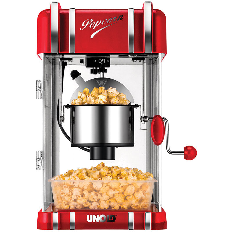 Eine rot-silberne Unold Popcornmaschine Retro mit frischem Popcorn darin, von dem etwas in eine durchsichtige Schale darunter läuft; oben ist „Popcorn“ und unten „Unold“ aufgedruckt.