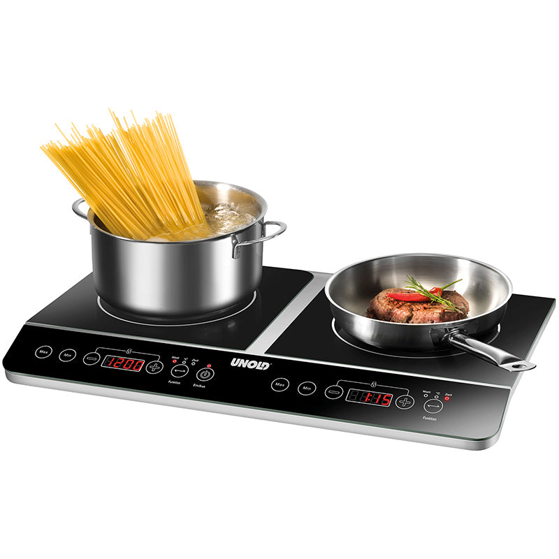 Die Unold Induktionskochplatte Doppel Elégance verfügt über digitale Anzeigen; auf der einen Seite werden Spaghetti in einem Topf gekocht, während auf der anderen Seite ein Steak mit Gemüse in einer Bratpfanne zubereitet wird.