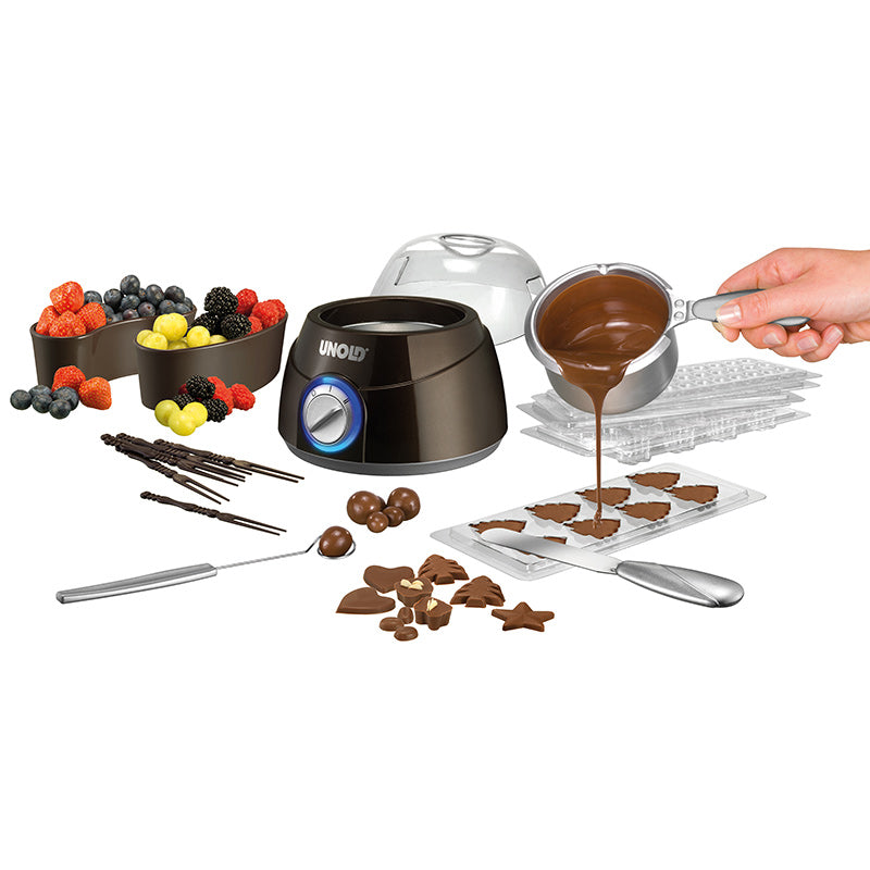 Das Unold-Chocolatier-Set umfasst einen Schmelztiegel, mit Früchten gefüllte Schalen, in Formen gegossene Schokolade, überzogene Leckereien und Utensilien – alles auf einem weißen Hintergrund.