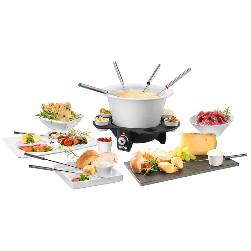 Das Unold Fondue Elégance-Set besteht aus einem Topf mit geschmolzenem Käse und Dip-Gabeln, umgeben von Tellern mit Brot, Gemüse, Trauben, Fleisch, Käsewürfeln und Dip-Saucen auf weißem Hintergrund.