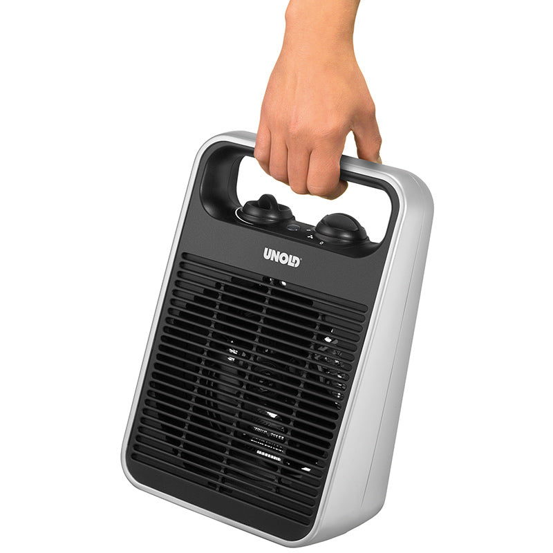 Eine Hand hält den Unold HEIZLÜFTER HANDLE, einen tragbaren schwarz-silbernen Elektroheizer mit einem oberen Griff, zwei Bedienknöpfen und einem Frontgitter.