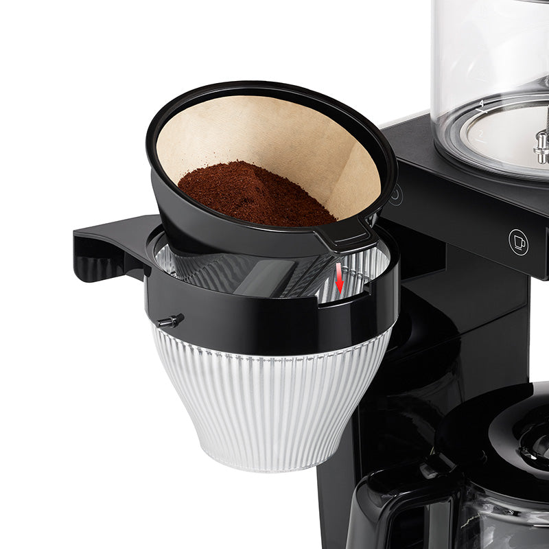 Eine Nahaufnahme des Unold Kaffeeautomaten Aroma Star zeigt seinen Filterkegel mit Papierfilter und gemahlenem Kaffee, der über dem geriffelten Glasbehälter der Maschine angebracht ist.